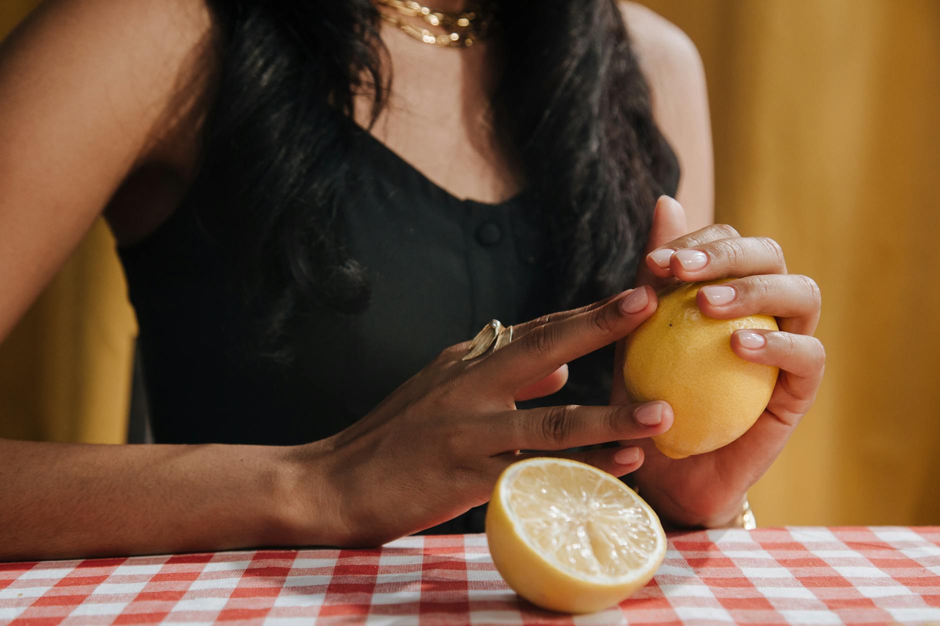 Hand holding a fresh lemon against a bright yellow background, representing renewed sensitivity and freshness