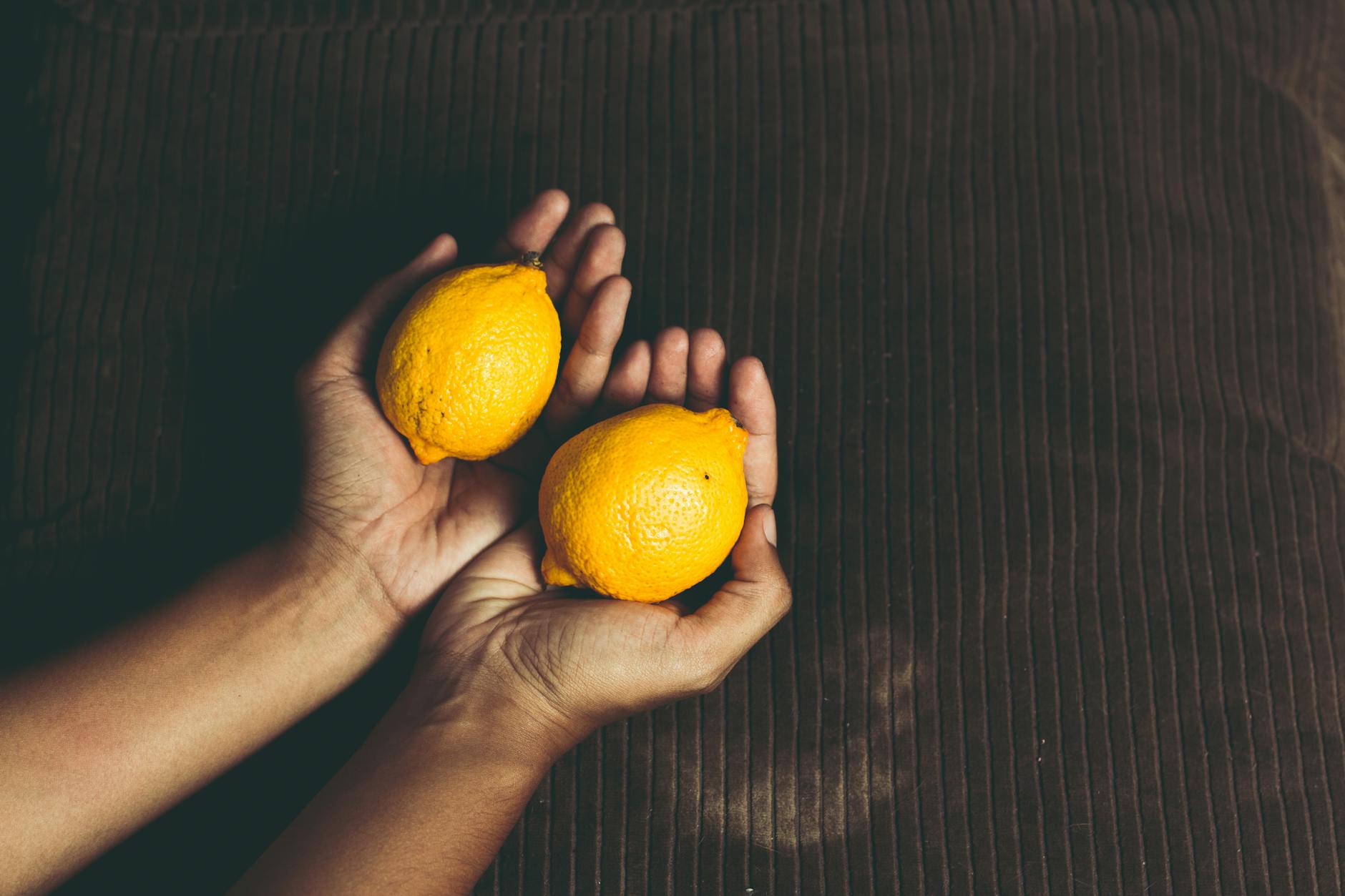 Fresh lemon halves on a pink background in sunlight, symbolizing the bright yellow Lemon vibrator