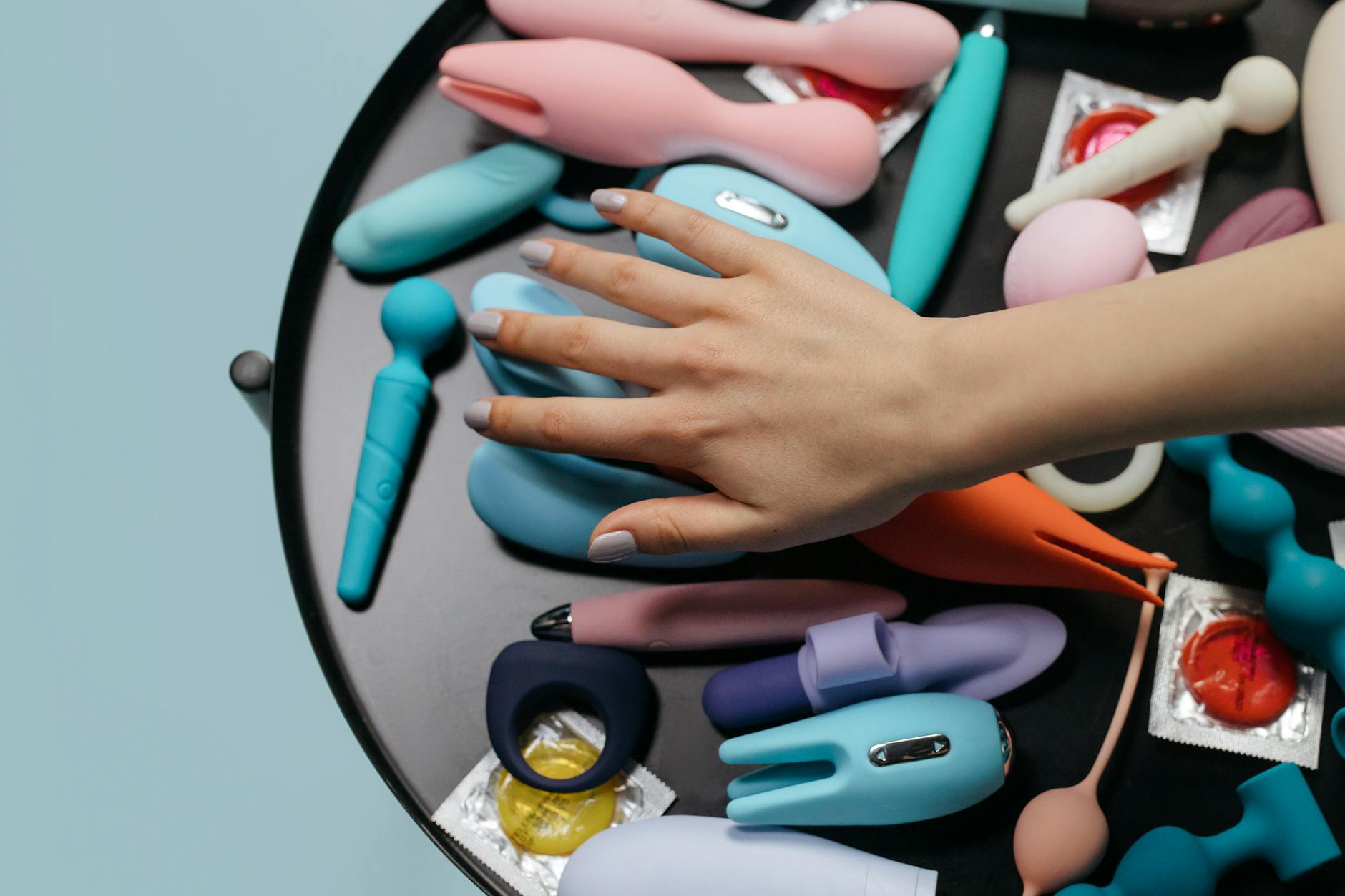Woman holding two colorful clitoral vibrators against a purple background