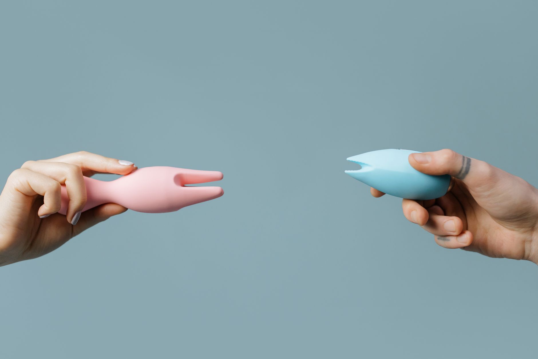 Hands holding a clitoral vibrator against a knitted sweater, intimate and relaxed