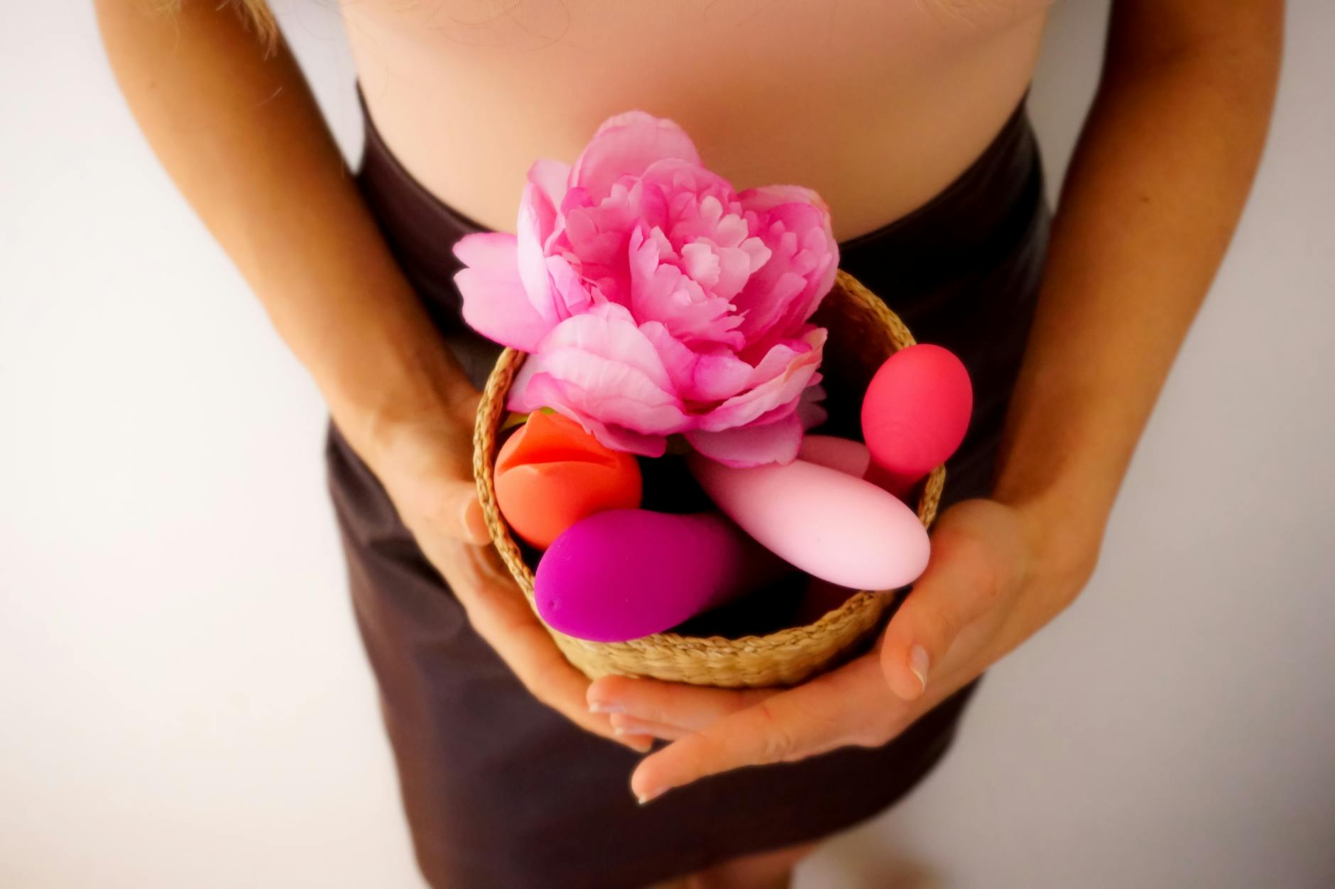 A hand holding a vibrator with art and personal items in background, symbolizing intimacy and self-care